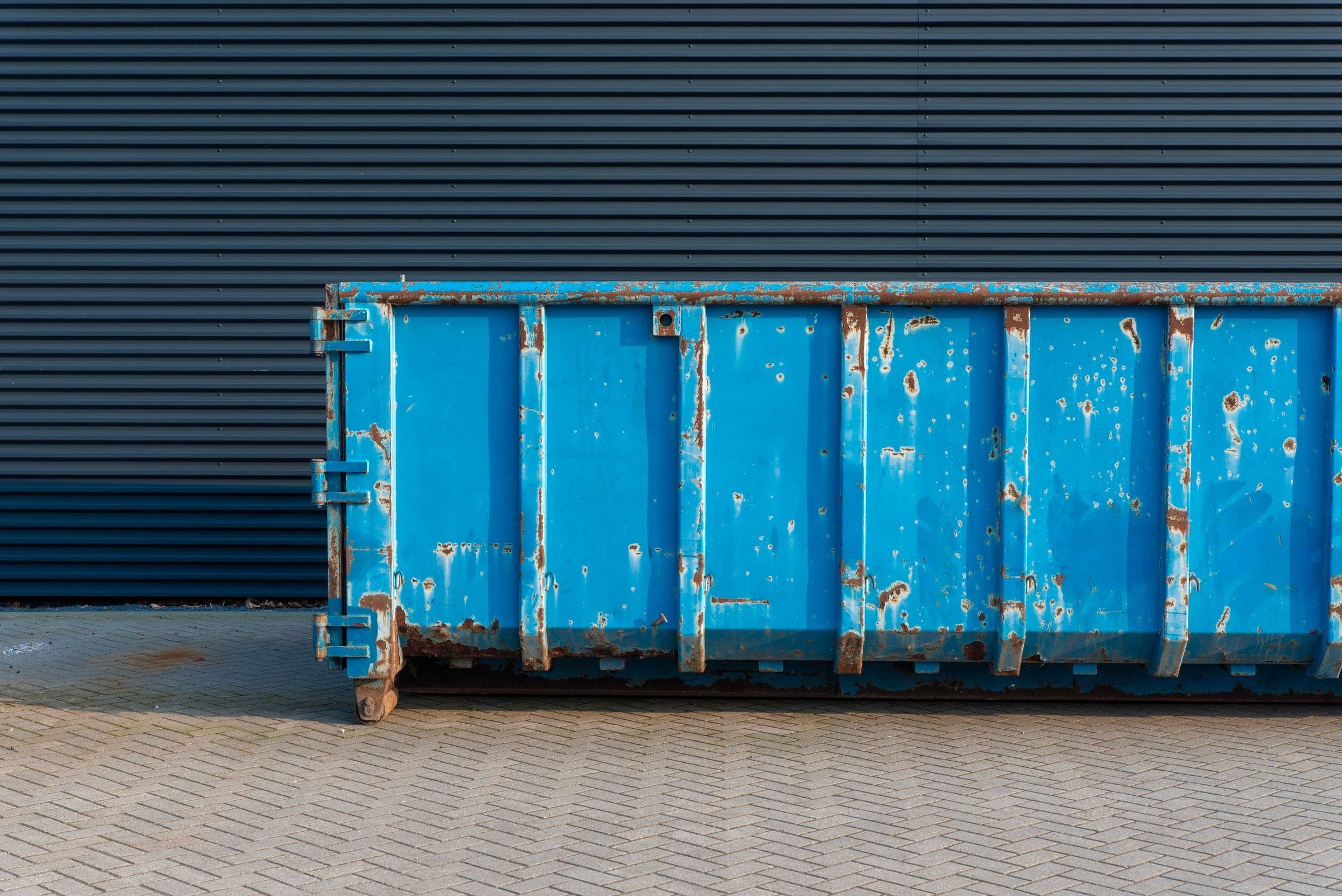 Blue steel roll-off dumpster parked on a paved lot, ready for delivery in Fayetteville NC